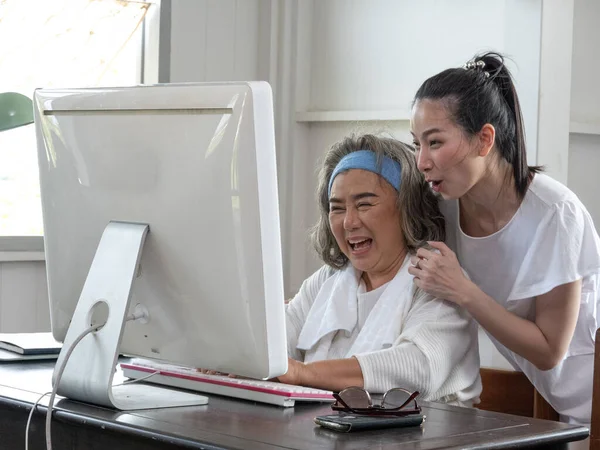 Adult daughter helps to elderly mother with computer usage, Family having fun watching movie on computer, buying via internet, store services concept.