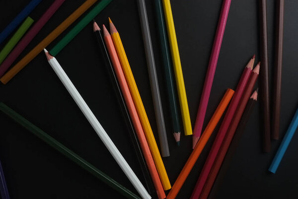 цветные карандаши на черном фоне
