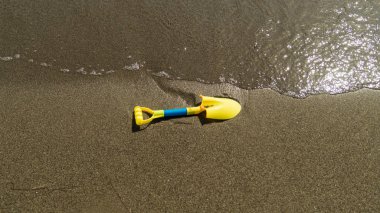 Çocuk oyuncak suya yakın plaj kum üzerinde. Renkli plastik kürek oyuncak.
