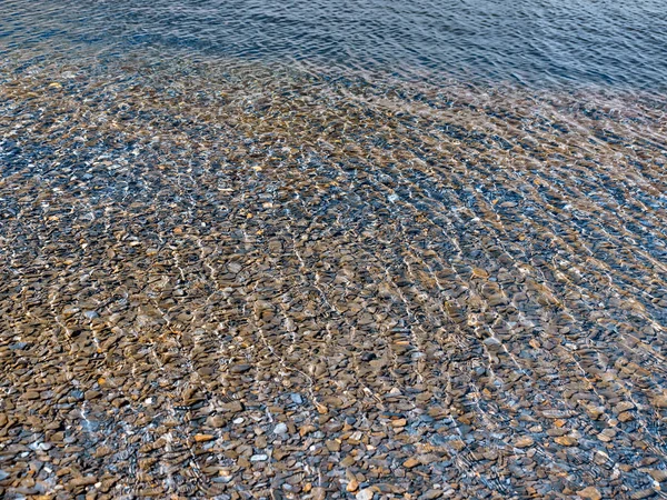 Pedras no fundo do lago com reflexão da luz do sol na água Fotografia De Stock