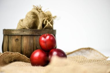 Bir sepet ve çuval bezi vintage bir arka plan üzerinde kırmızı erik