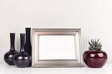 Aloe ve vazo ile beyaz bir tabloda boş gümüş çerçeve. Mockup kopya alanı ile