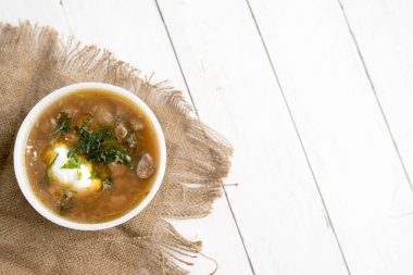 Chunky Italian wedding soup on a light wood background table clipart