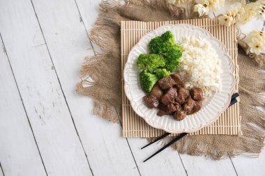 Beyaz pirinç üzerinde sığır eti ve brokoli Çin yemeği. hafif ahşap arka plan masasında