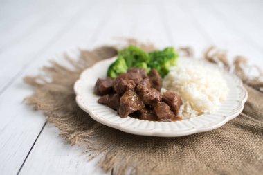 Beyaz pirinç üzerinde sığır eti ve brokoli Çin yemeği. hafif ahşap arka plan masasında