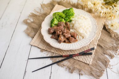 Beyaz pirinç üzerinde sığır eti ve brokoli Çin yemeği. hafif ahşap arka plan masasında