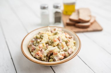 Bir kase geleneksel Rus salatası, adı Olivie, Rus Yeni Yılı ya da tahta arka planda Noel salatası. Pişmiş sebzelerden salata. Patates salatası.