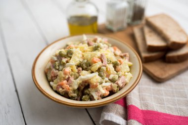 Bir kase geleneksel Rus salatası, adı Olivie, Rus Yeni Yılı ya da tahta arka planda Noel salatası. Pişmiş sebzelerden salata. Patates salatası.