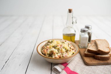 Bir kase geleneksel Rus salatası, adı Olivie, Rus Yeni Yılı ya da tahta arka planda Noel salatası. Pişmiş sebzelerden salata. Patates salatası.