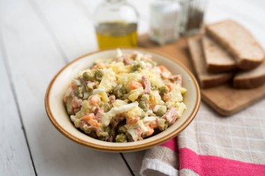 Bir kase geleneksel Rus salatası, adı Olivie, Rus Yeni Yılı ya da tahta arka planda Noel salatası. Pişmiş sebzelerden salata. Patates salatası.