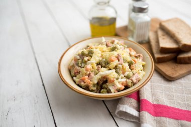 Bir kase geleneksel Rus salatası, adı Olivie, Rus Yeni Yılı ya da tahta arka planda Noel salatası. Pişmiş sebzelerden salata. Patates salatası.