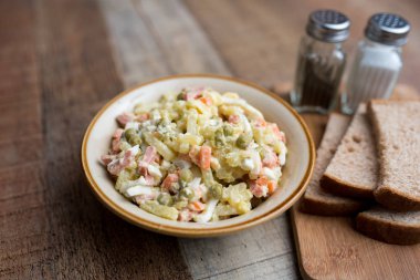 Bir kase geleneksel Rus salatası, adı Olivie, Rus Yeni Yılı ya da tahta arka planda Noel salatası. Pişmiş sebzelerden salata. Patates salatası.