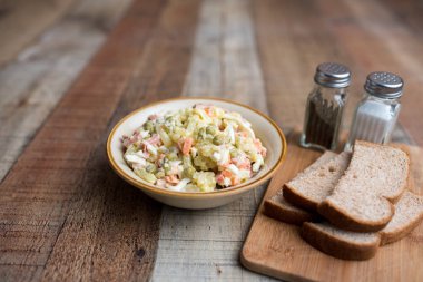 Bir kase geleneksel Rus salatası, adı Olivie, Rus Yeni Yılı ya da tahta arka planda Noel salatası. Pişmiş sebzelerden salata. Patates salatası.