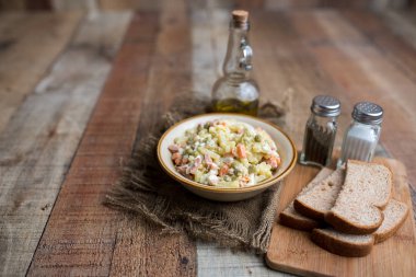 Bir kase geleneksel Rus salatası, adı Olivie, Rus Yeni Yılı ya da tahta arka planda Noel salatası. Pişmiş sebzelerden salata. Patates salatası.