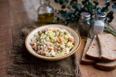 Bir kase geleneksel Rus salatası, adı Olivie, Rus Yeni Yılı ya da tahta arka planda Noel salatası. Pişmiş sebzelerden salata. Patates salatası.