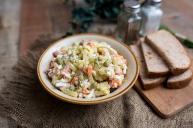 Bir kase geleneksel Rus salatası, adı Olivie, Rus Yeni Yılı ya da tahta arka planda Noel salatası. Pişmiş sebzelerden salata. Patates salatası.
