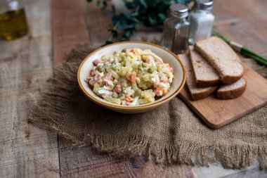Bir kase geleneksel Rus salatası, adı Olivie, Rus Yeni Yılı ya da tahta arka planda Noel salatası. Pişmiş sebzelerden salata. Patates salatası.