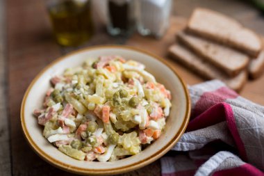 Bir kase geleneksel Rus salatası, adı Olivie, Rus Yeni Yılı ya da tahta arka planda Noel salatası. Pişmiş sebzelerden salata. Patates salatası.