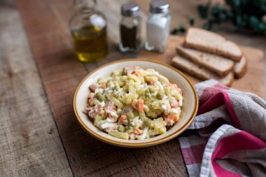 Bir kase geleneksel Rus salatası, adı Olivie, Rus Yeni Yılı ya da tahta arka planda Noel salatası. Pişmiş sebzelerden salata. Patates salatası.