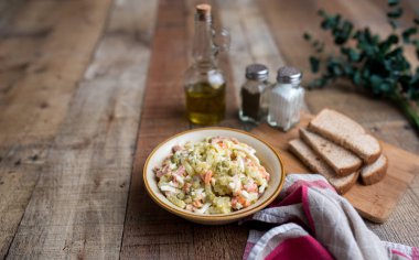 Bir kase geleneksel Rus salatası, adı Olivie, Rus Yeni Yılı ya da tahta arka planda Noel salatası. Pişmiş sebzelerden salata. Patates salatası.