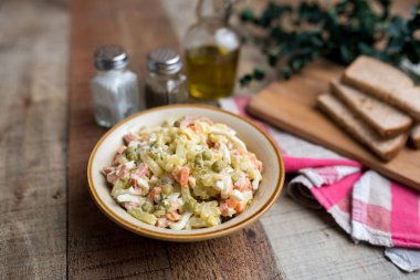 Bir kase geleneksel Rus salatası, adı Olivie, Rus Yeni Yılı ya da tahta arka planda Noel salatası. Pişmiş sebzelerden salata. Patates salatası.