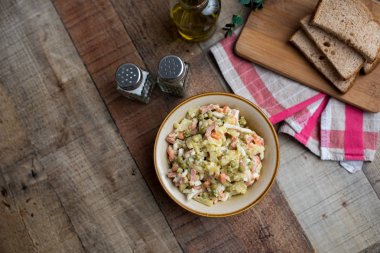 Bir kase geleneksel Rus salatası, adı Olivie, Rus Yeni Yılı ya da tahta arka planda Noel salatası. Pişmiş sebzelerden salata. Patates salatası.