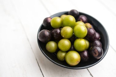 Muscadine üzüm de bataklık üzüm, ahşap arka plan üzerinde bir kase florida üzüm olarak bilinir