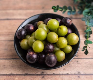 Muscadine üzüm de bataklık üzüm, ahşap arka plan üzerinde bir kase florida üzüm olarak bilinir