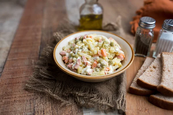 Bir kase geleneksel Rus salatası, adı Olivie, Rus Yeni Yılı ya da tahta arka planda Noel salatası. Pişmiş sebzelerden salata. Patates salatası.