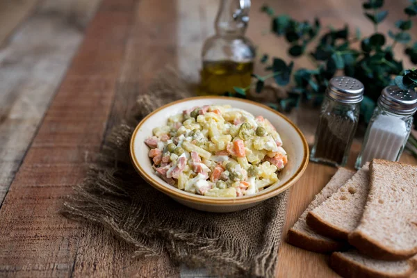 Bir kase geleneksel Rus salatası, adı Olivie, Rus Yeni Yılı ya da tahta arka planda Noel salatası. Pişmiş sebzelerden salata. Patates salatası.