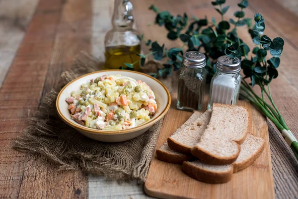 Bir kase geleneksel Rus salatası, adı Olivie, Rus Yeni Yılı ya da tahta arka planda Noel salatası. Pişmiş sebzelerden salata. Patates salatası.
