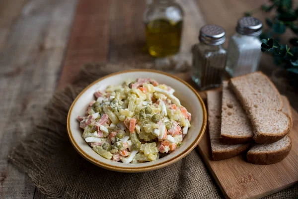 Bir kase geleneksel Rus salatası, adı Olivie, Rus Yeni Yılı ya da tahta arka planda Noel salatası. Pişmiş sebzelerden salata. Patates salatası.