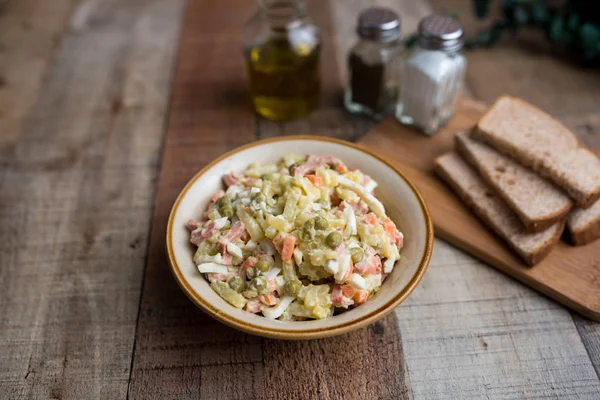 Bir kase geleneksel Rus salatası, adı Olivie, Rus Yeni Yılı ya da tahta arka planda Noel salatası. Pişmiş sebzelerden salata. Patates salatası.