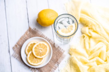 Limon dilimleri ve nane şekerli soğuk detoks suyu beyaz ahşap bir masada.