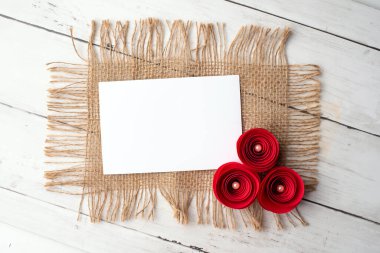 Marka kimliği için bir model. Boş beyaz kartın fotoğrafı. Portföy ve proje sunumu için boş kart. Klasik çuval bezi ve kağıt güller.