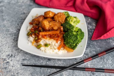 Brokoli ve pilav ile servis edilen portakallı tavuk kızartması.