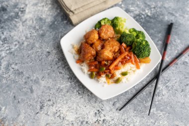 Brokoli ve pilav ile servis edilen portakallı tavuk kızartması.