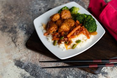 Brokoli ve pilav ile servis edilen portakallı tavuk kızartması.