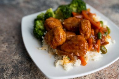 Brokoli ve pilav ile servis edilen portakallı tavuk kızartması.