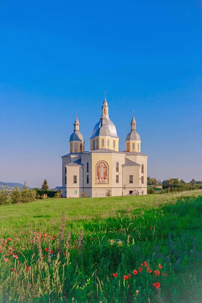 Templo santo en una colina con amapolas contra un cielo despejado . — Foto de Stock