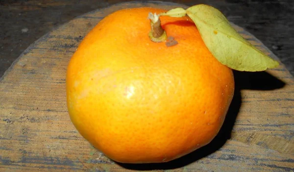 その一番おいしい状態でマンダリンこの柑橘類は 木製の腰掛けの唯一のオブジェクトと構成で公開されてオレンジ色のトーンをカットします — ストック写真