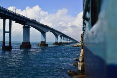 Pamban Köprüsü denilen deniz üzerindeki demiryolu köprüsünde Hint demiryolu treni. Adadaki Rameswaram'ı anakaraya bağlıyor. Sol tarafta uzun yol köprüsü var. Çoğunlukla mavi renkli.