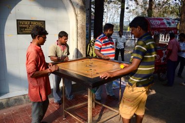 Kalküta, Hindistan - Mart, 2014: Karrom oyunu oynayan Hintli erkekler - geleneksel masa oyunu. Genç yetişkinler Kalküta bilardo benzer masa oyunu zevk sokakta eğlenin.