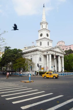 Kalküta, Hindistan - Mart, 2014: Kalküta'daki eski Katolik St. Andrew kilisesinin önünde kavşakta sarı taksi Büyükelçisi