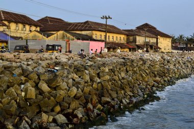 Thalassery, Kerala, Hindistan-Ocak, 2017: Hint insanlar Breakwater taşlar üzerinde oturan ve gün batımı zevk. Taş kıyı.
