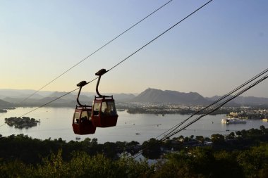 İki asılı kabin Mansapurna şur Mata teleferik ve açık mavi gökyüzü ile Pichola Gölü, Udaipur, Rajasthan, Hindistan panoramik görünümü