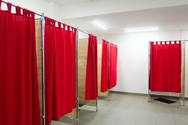 Kırmızı perdeler ve beyaz duvarlar ile boş uygun odalar. Hiçbir kişi ile giyim mağazasında giyinme odaları