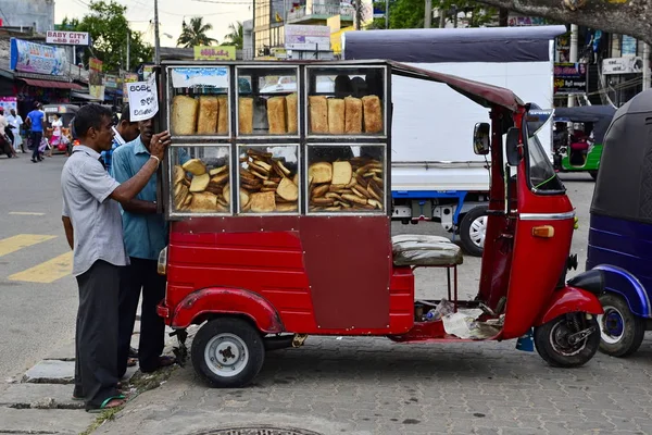 Weligama, Sri Lanka-Nisan, 2017: adam kırmızı üç tekerlekli araç (tuk tuk) sokak pazarında ekmek satan