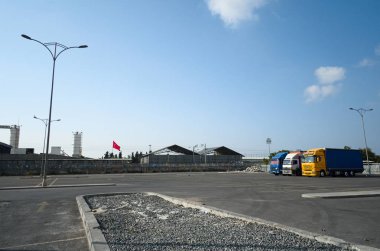 İstanbul, Türkiye-Eylül, 2018: Istanbul şehir sanayi bölgesinde nakliye için yük arabaları için neredeyse boş bir otopark üzerinde kargo ile üç ağır kamyonlar.