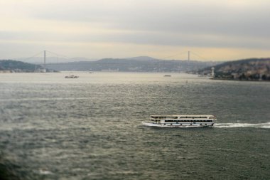 Istanbul 'un Asya ve Avrupa taraflarını bağlayan bir arka planda Bosporus ve Boğaziçi Köprüsünde feribot. Tilt-Shift efekti ile üretilmiştir. Bir teknede seçici odaklama ve bulanık arka plan